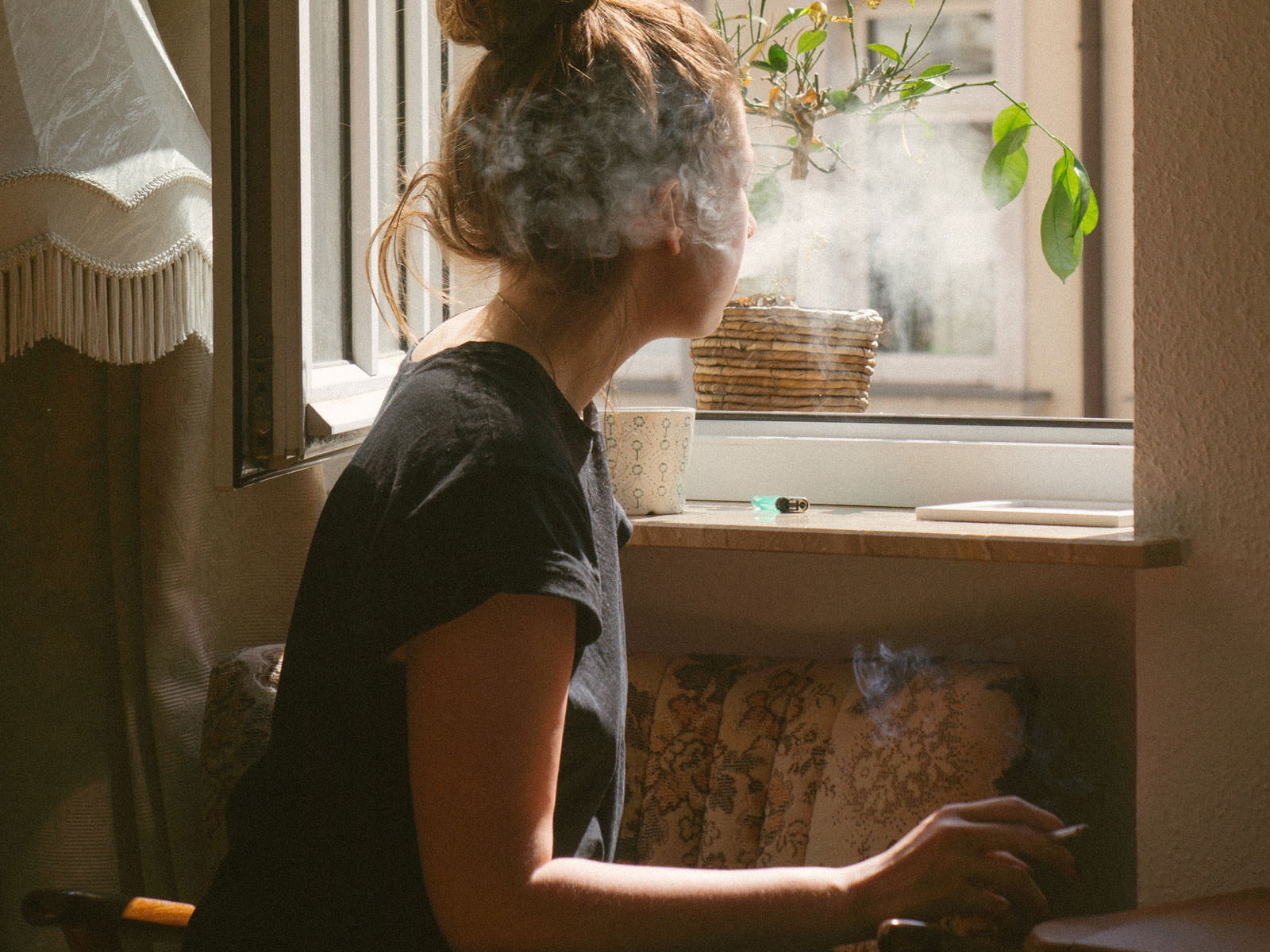 Woman smoking cannabis joint looking out window