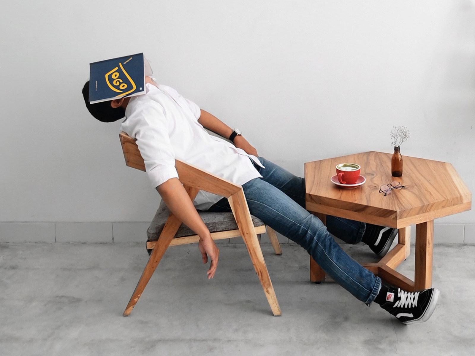 Person sleeping at table with book on head