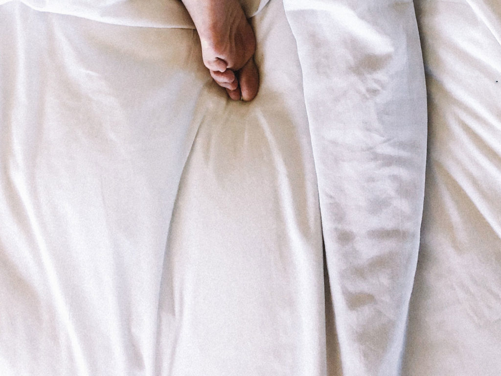 Bare foot on bed with white sheets